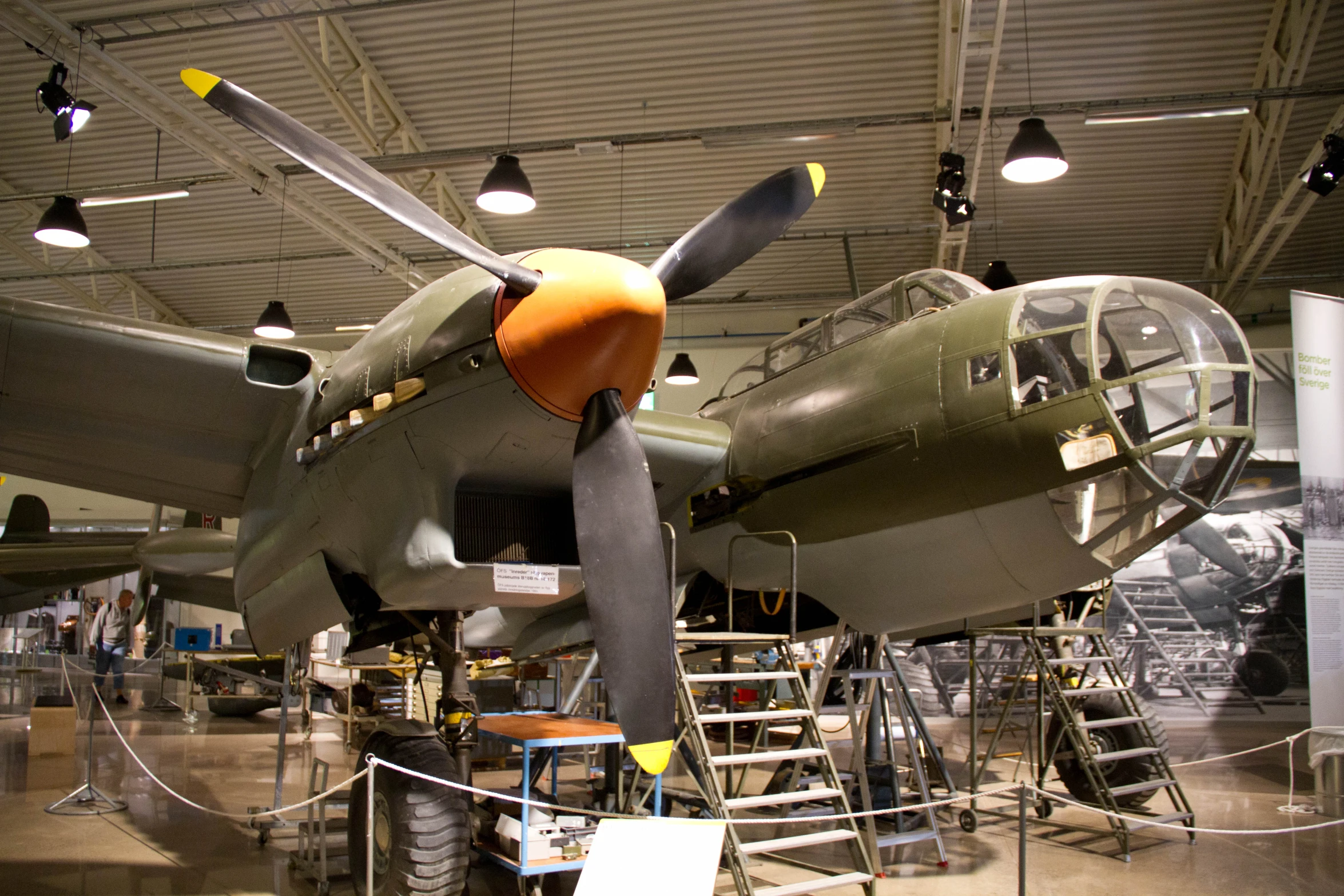 old plane in hangar with ladder and lights