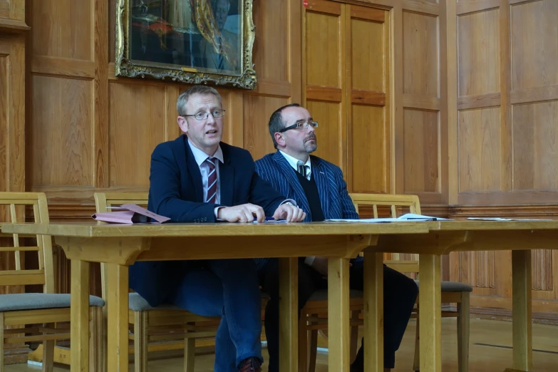 two businessmen sitting at a wooden table together