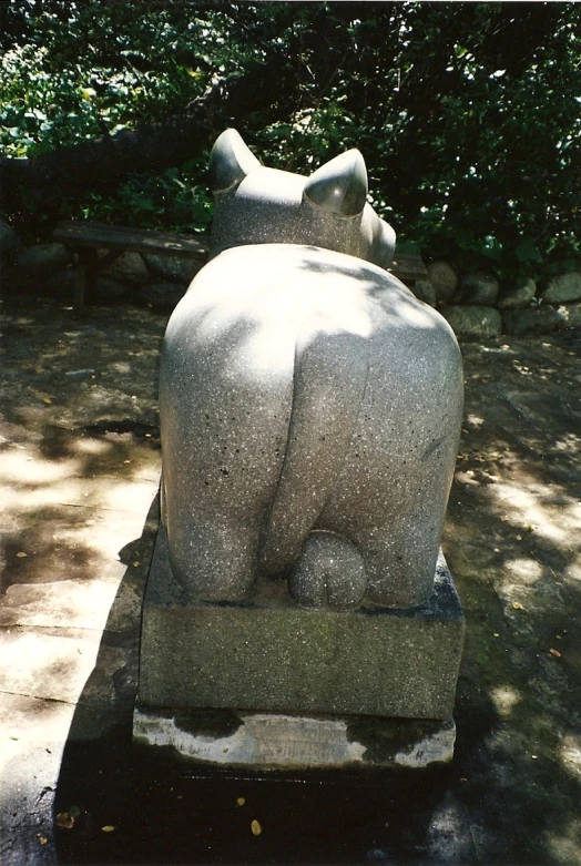 a statue is sitting in the shade under some trees