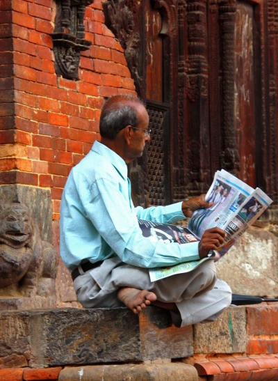 a man sitting on top of steps reading a paper