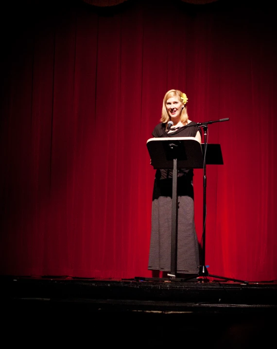 a woman standing in front of a microphone on top of a stage