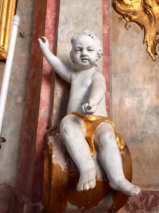 a statue of a  baby in a corner of an antique building