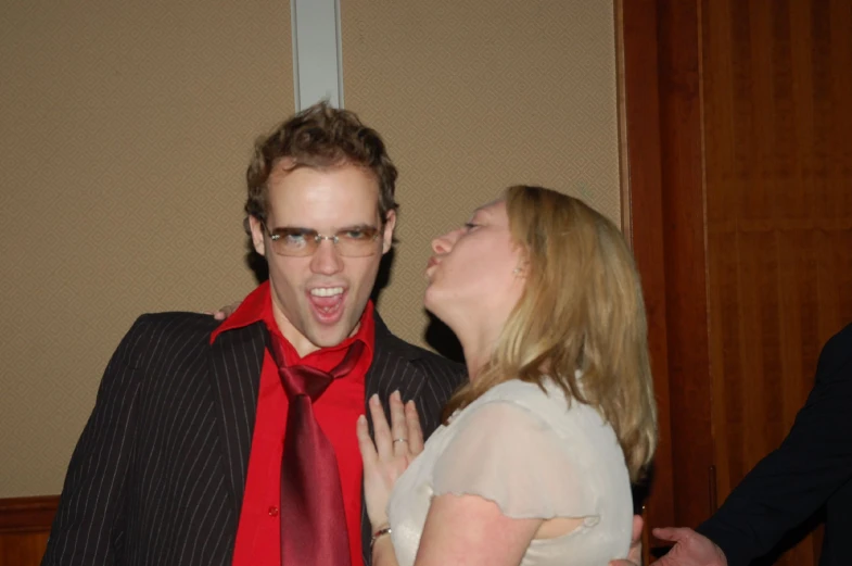 a man in glasses and tie giving a girl a kiss