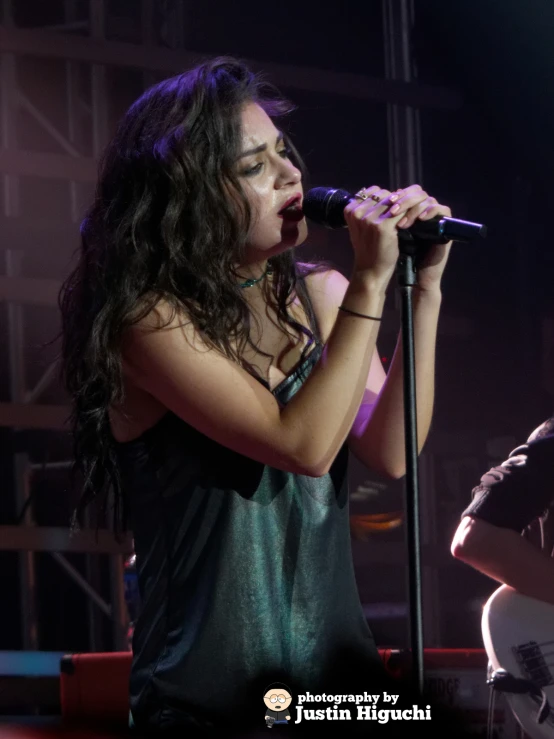 woman singing into a microphone on stage