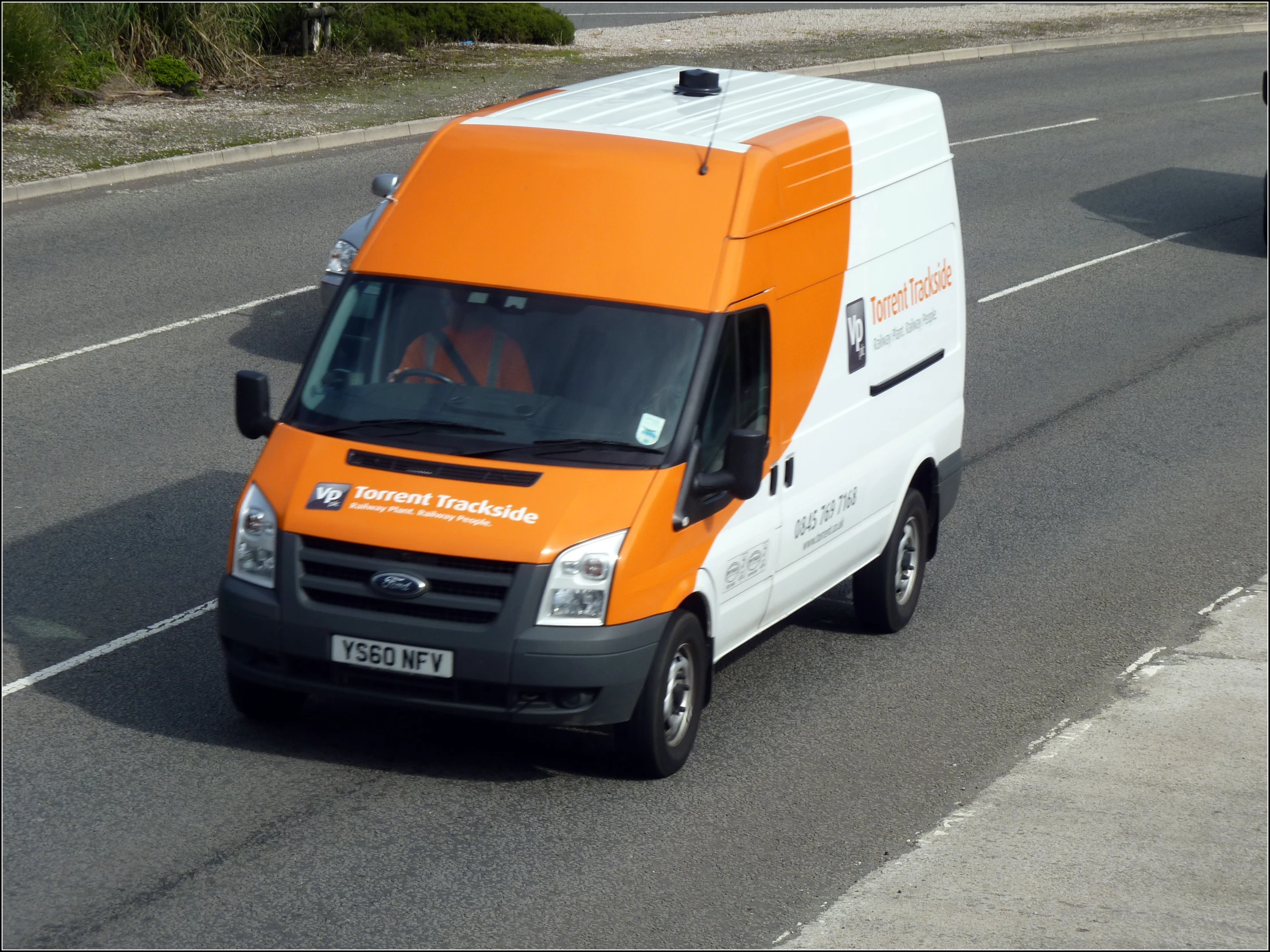 an orange and white truck drives on a road