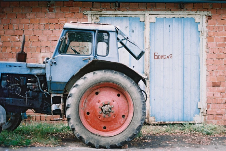 a tractor with an orange rim parked near a building