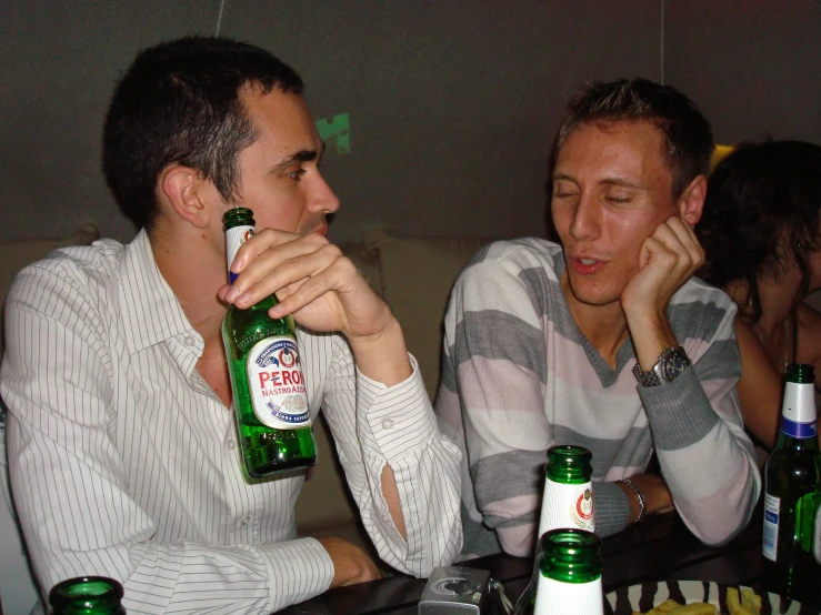 two people sit at a table with alcohol bottles