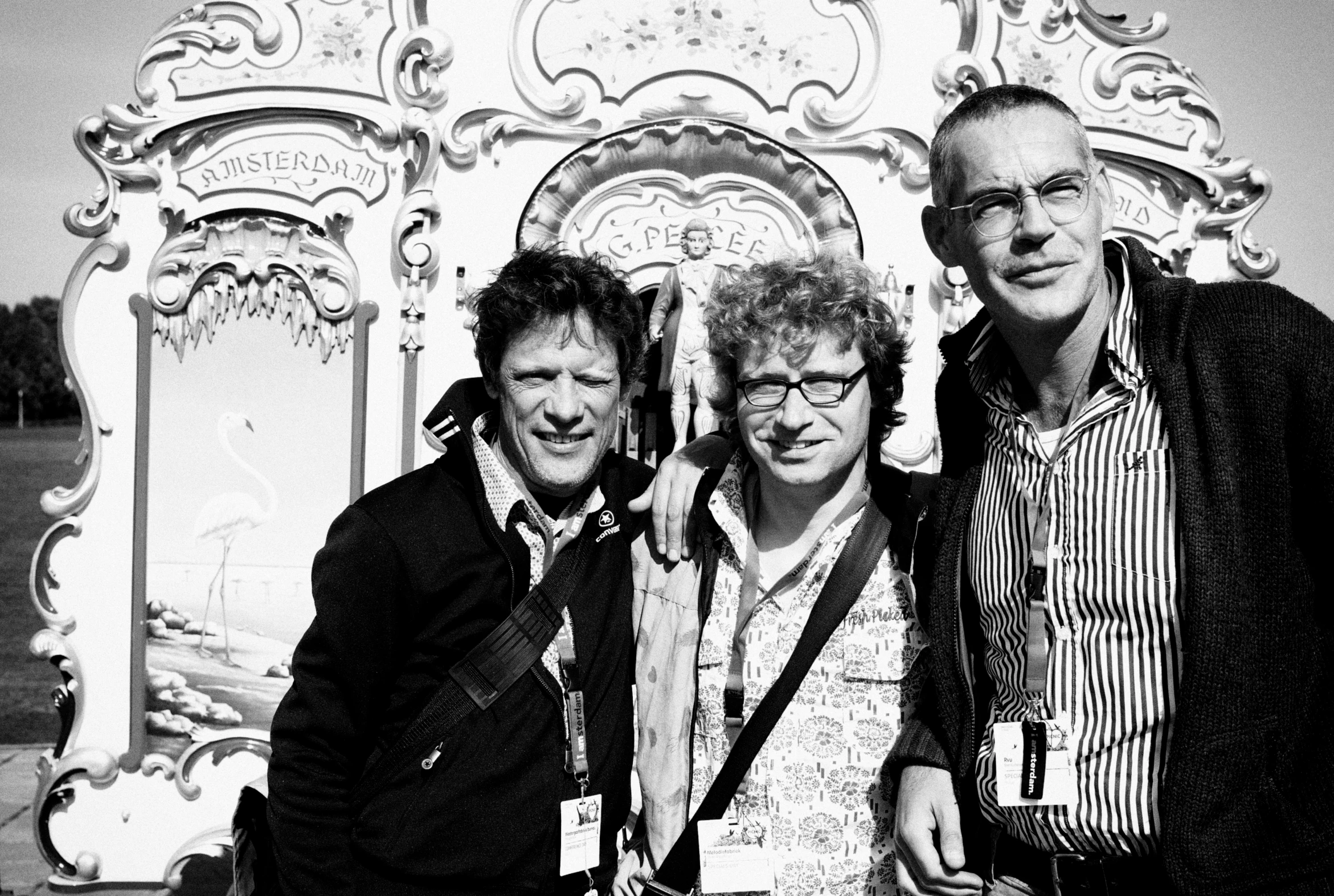 three men standing in front of a large sculpture