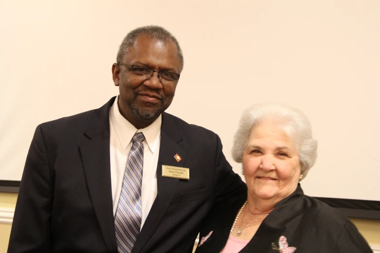 a man in suit and tie standing next to a woman