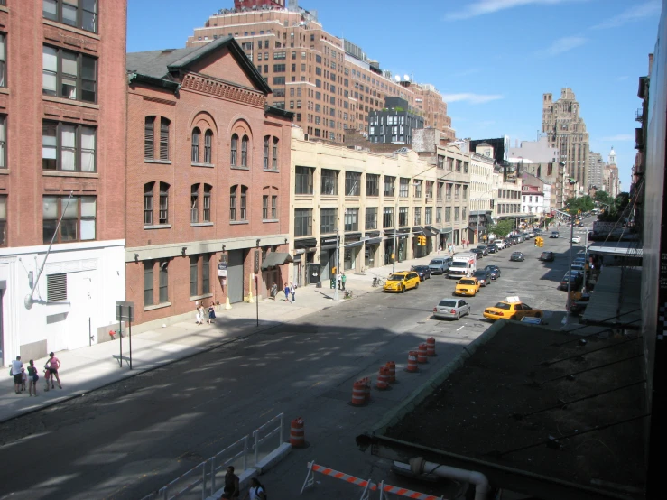street and buildings with construction cones and people on the sidewalk