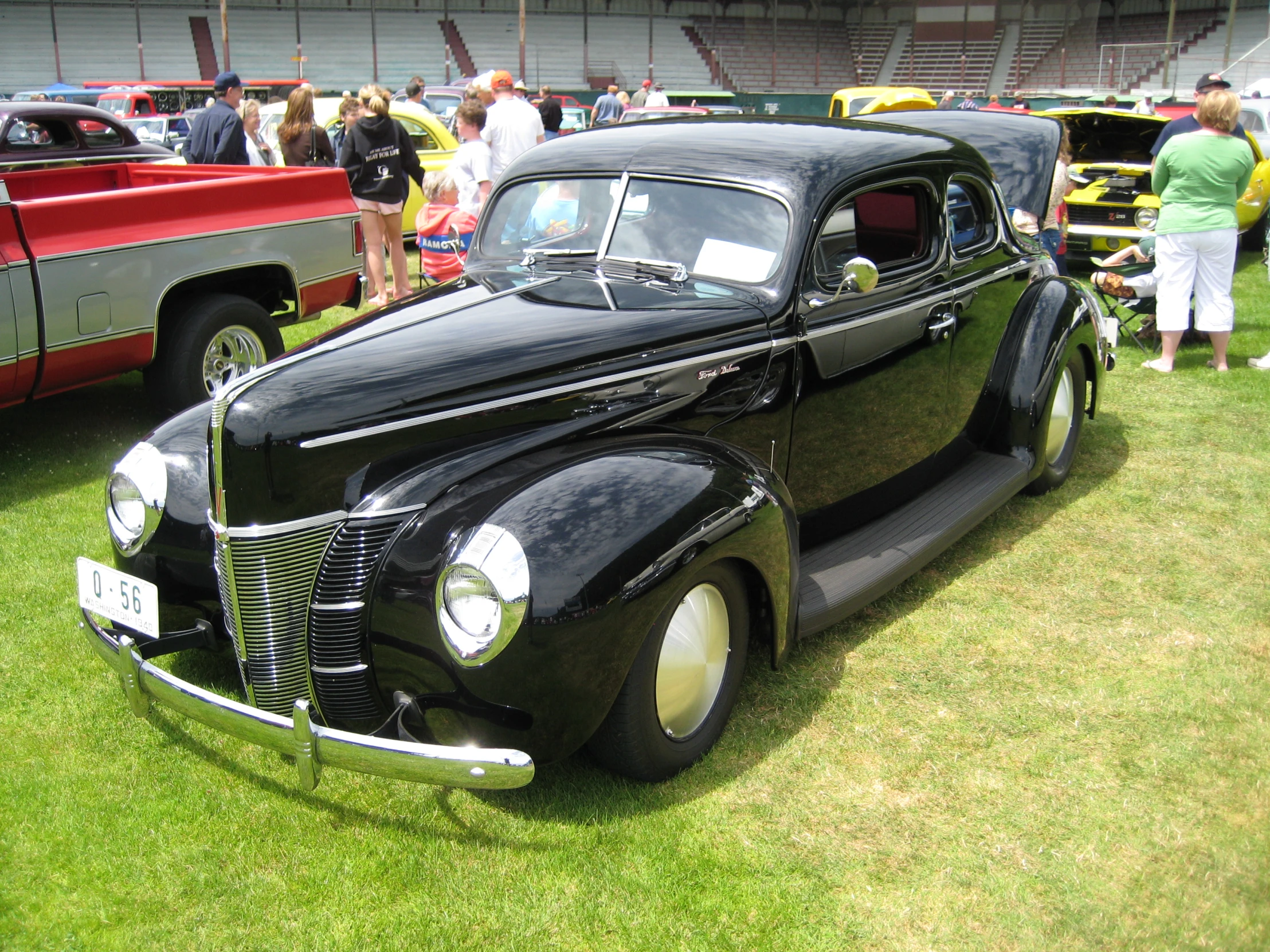 classic black car parked at a car show in grass