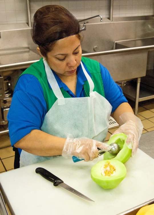 a woman cuts green fruit into slices with scissors