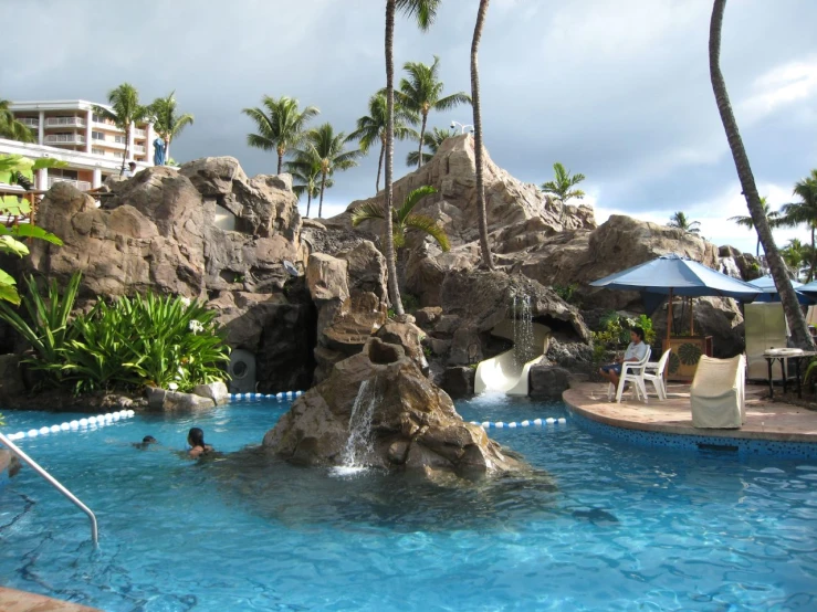an outdoor swimming pool with waterfall at an resort