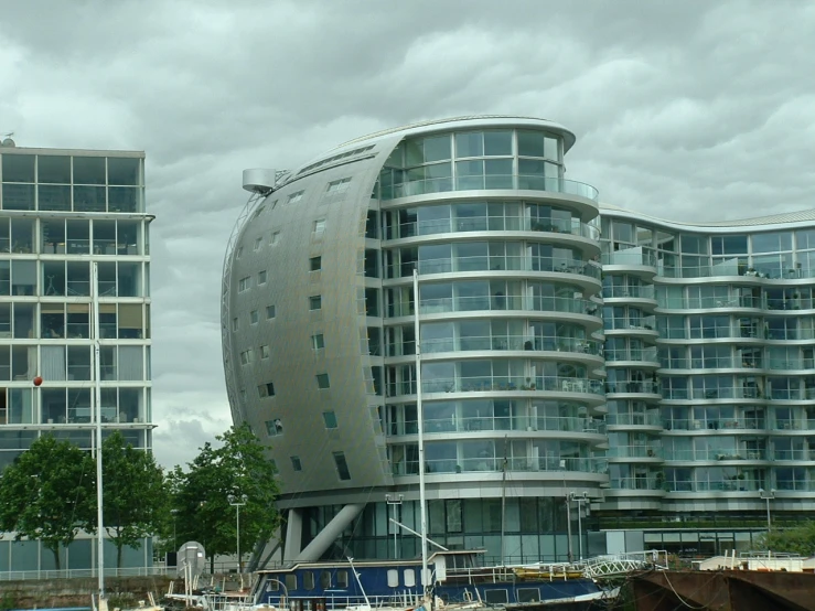 there is a tall curved building on the water