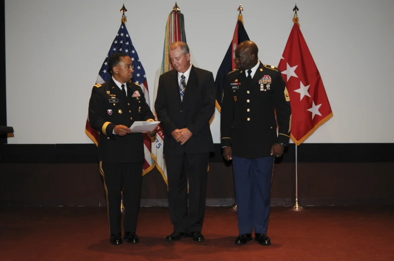 two men in uniform are standing on a stage with flags