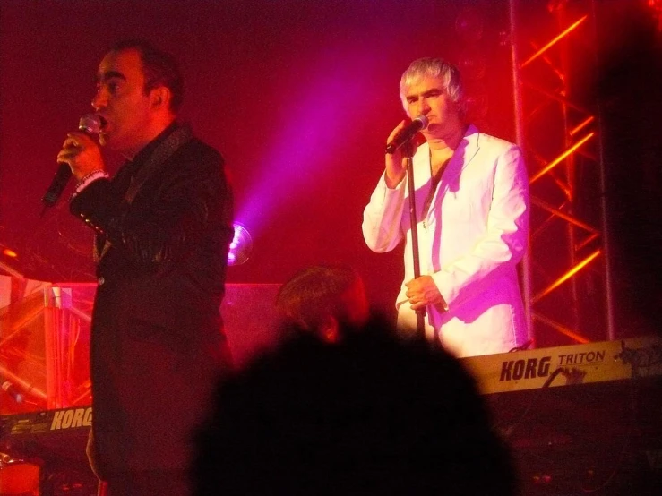 two people on stage with microphones with purple light
