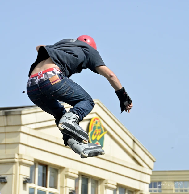 a man wearing a red helmet and knee pads jumping in the air on his skateboard