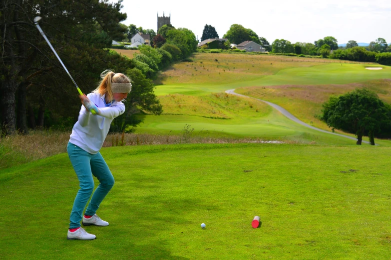 a woman swings her golf club at the green