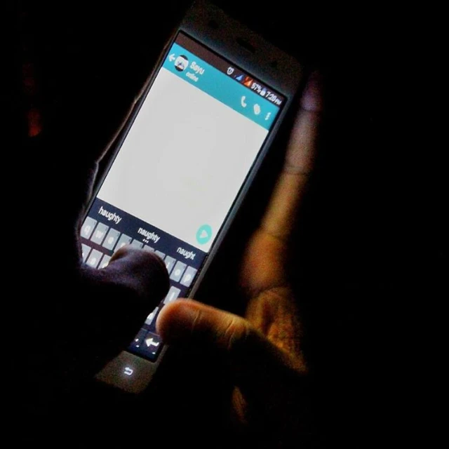 a hand is holding a cellphone in the dark