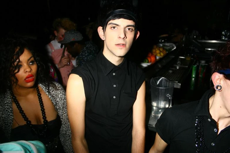 two people sitting in front of a bar, with one person wearing a black shirt and the other is looking into the camera