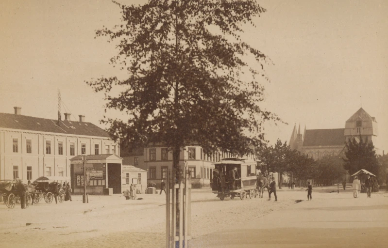 a black and white pograph of a horse drawn carriage on the street