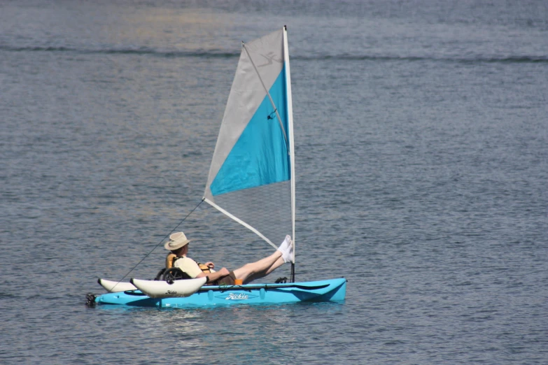 a man riding on top of a small blue sail boat