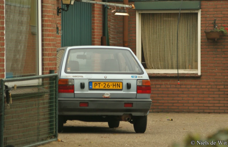 a small car parked in front of a red brick building