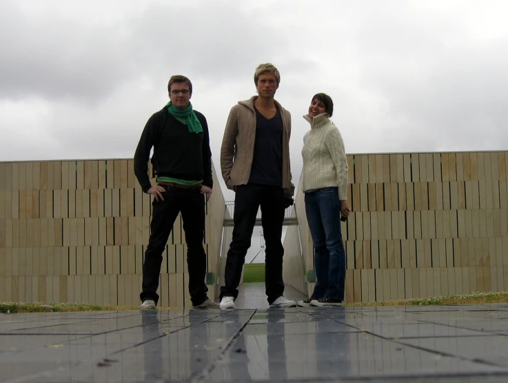 three people standing next to each other near a building