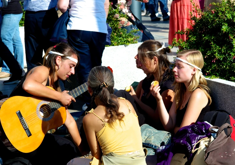 girls are playing guitar and talking outside