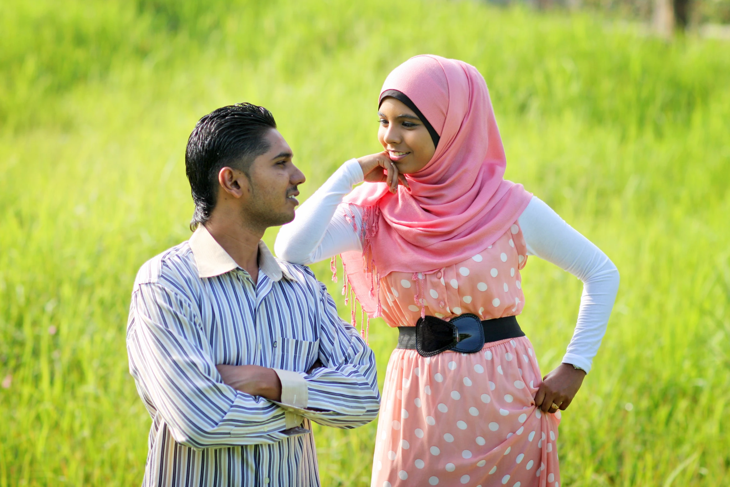 a young man standing next to a young woman in a pink dress