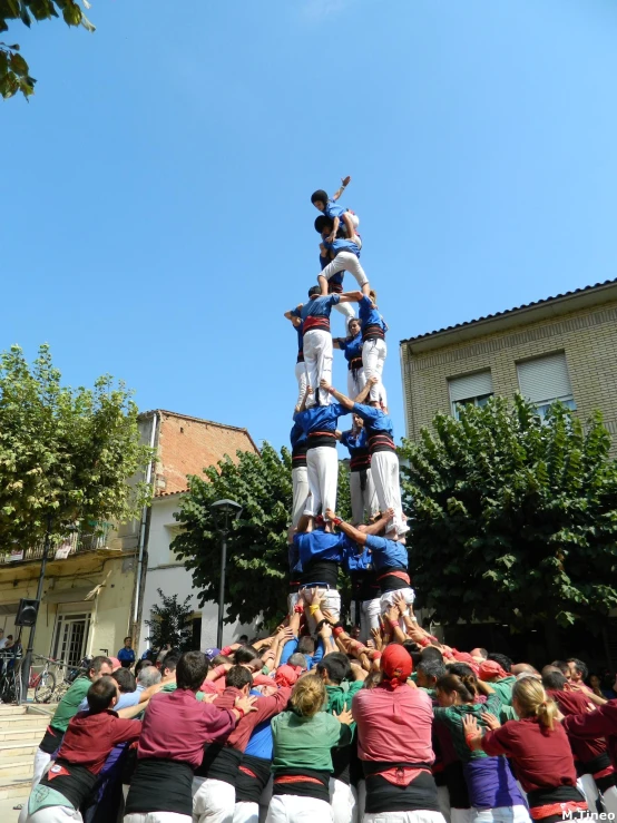 men in white uniforms doing tricks with each other on a pole