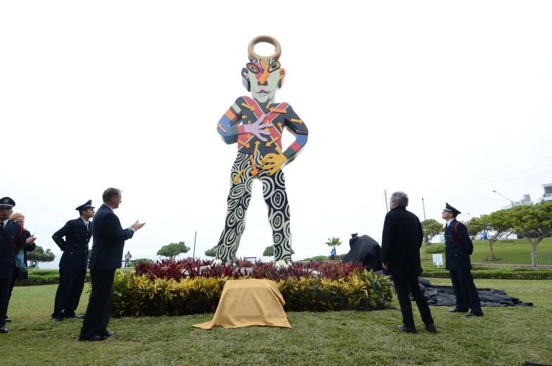 a group of people are standing in front of a giant sculpture