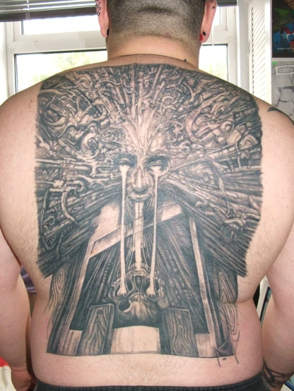 a man with a tattoo on his back who is wearing a suit of armor