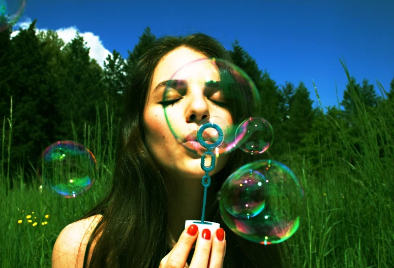 a woman blowing soap bubbles with her fingers