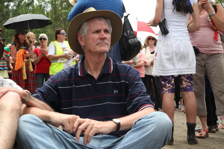 a man in a large hat looks at the camera as others look on