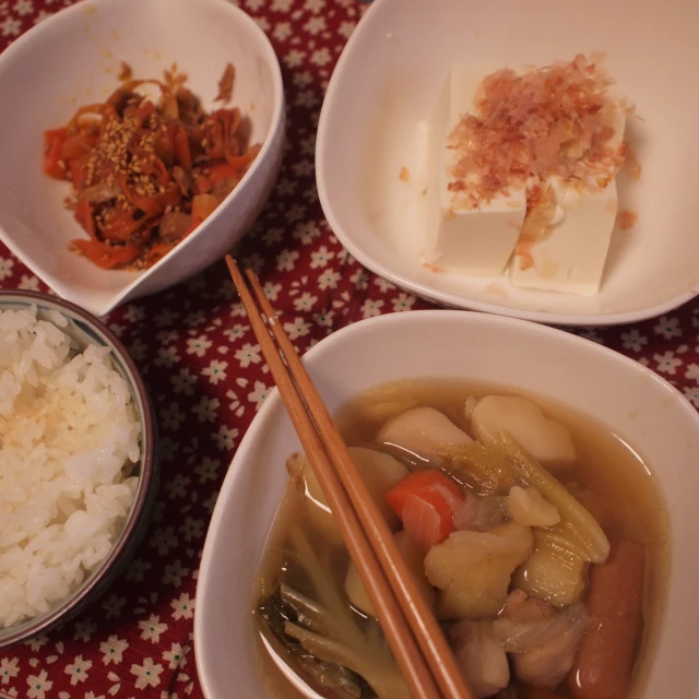 three plates with rice, chopsticks and vegetables
