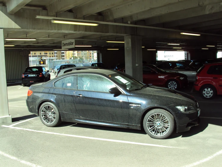 a grey car parked next to two cars in a parking garage