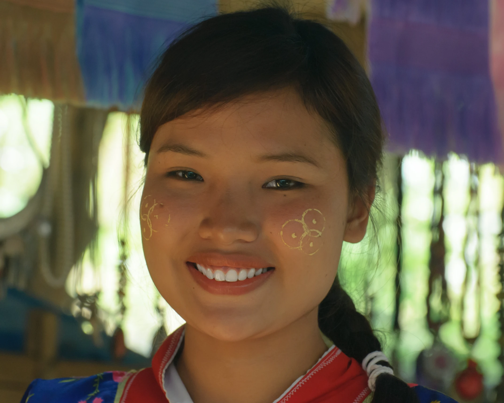 a  smiling at the camera with two little circles painted on her face