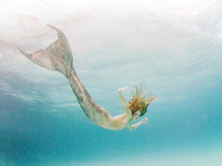 a mermaid is swimming in the blue water