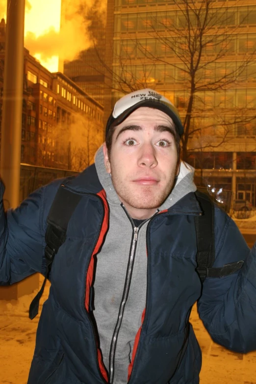 a person wearing a hoodie with a large fire behind him