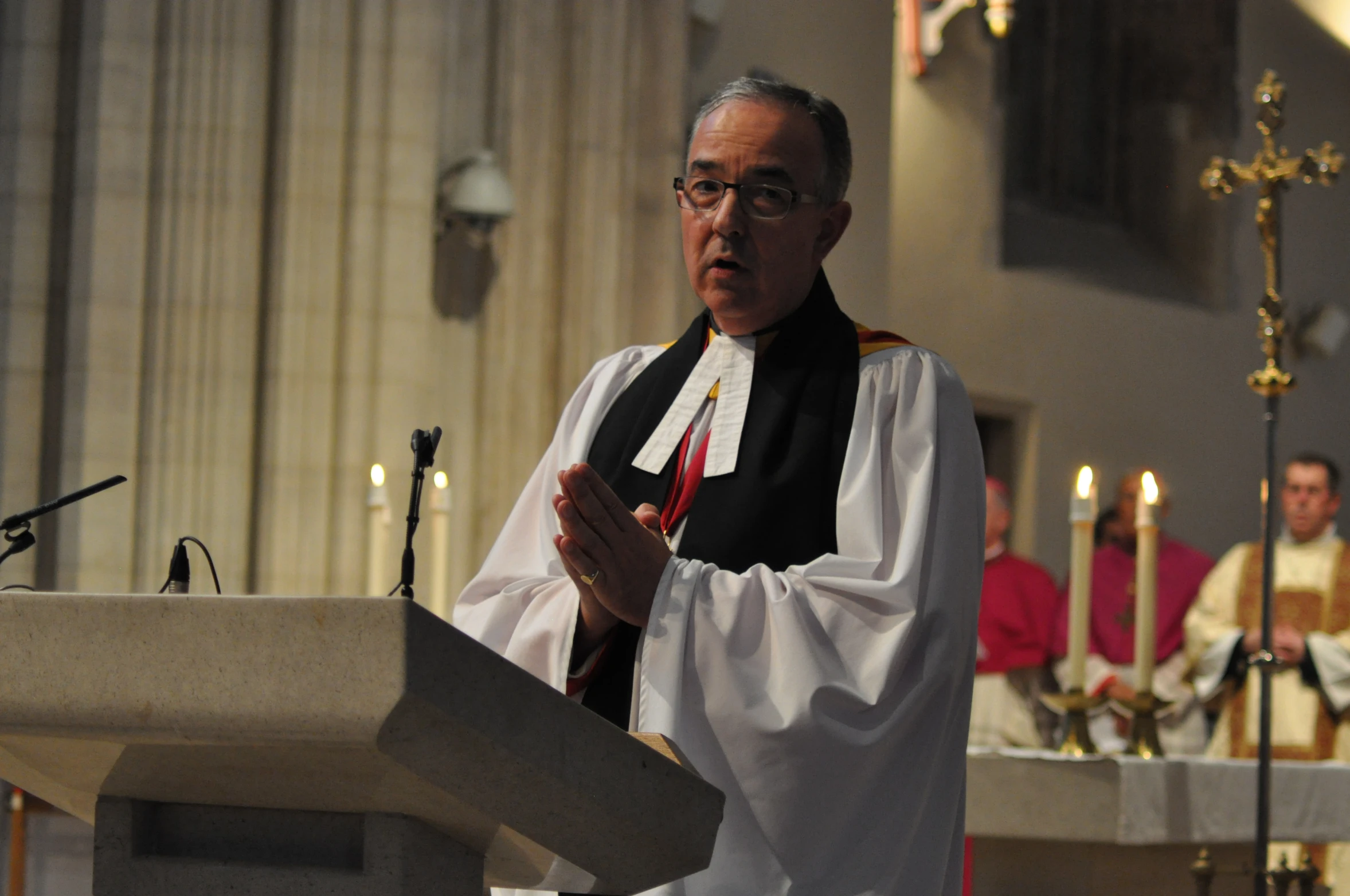 a priest standing at a podium with microphone