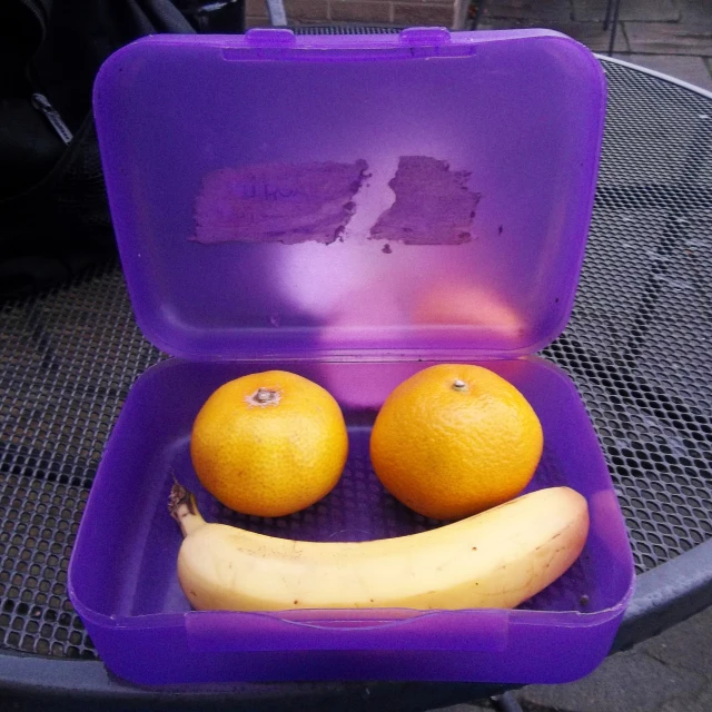 two oranges in a purple container sitting on top of a table