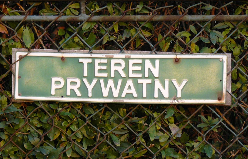 a green street sign sitting on top of a metal fence