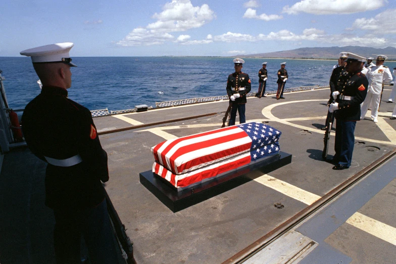 a casket on a ship with men in navy uniforms