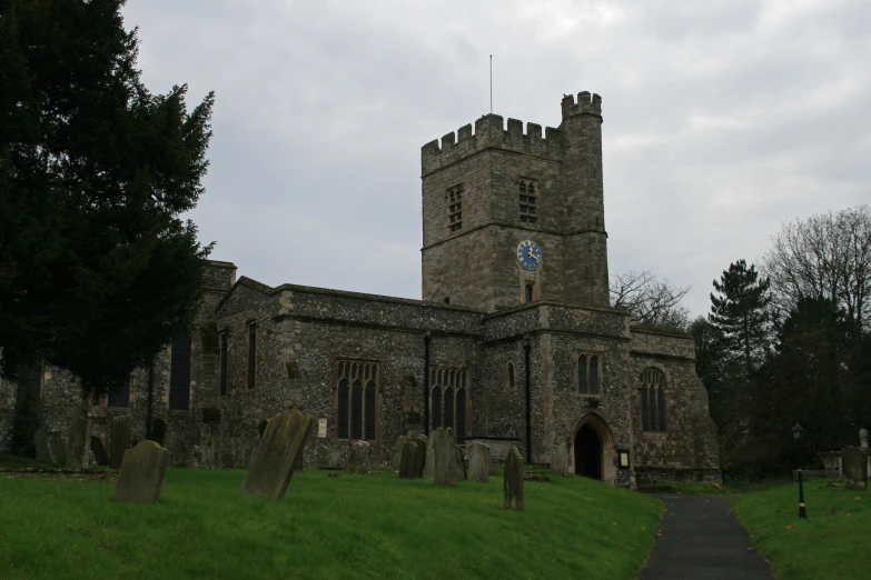 a stone church in an old graveyard with a clock tower