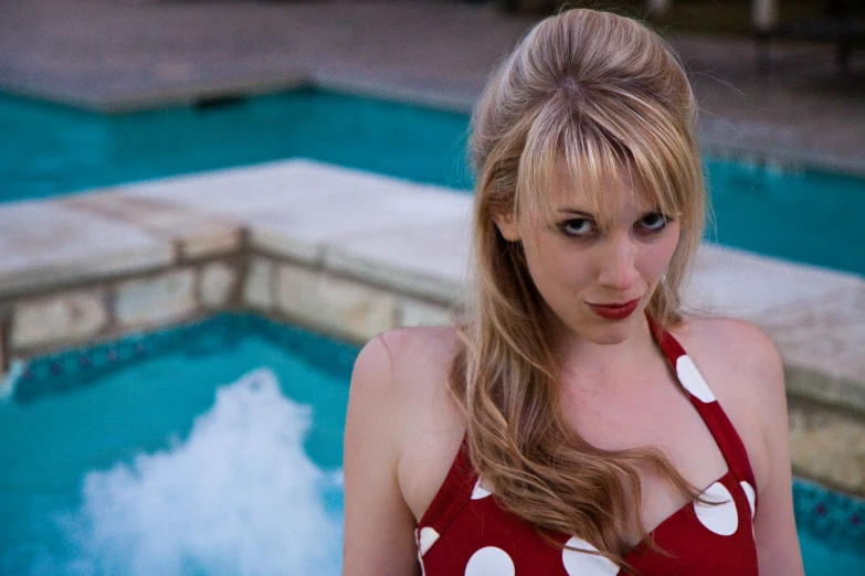 a woman standing next to a swimming pool