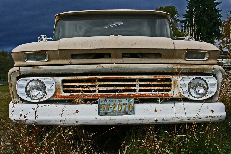 an old rusted out pickup truck sits in the grass