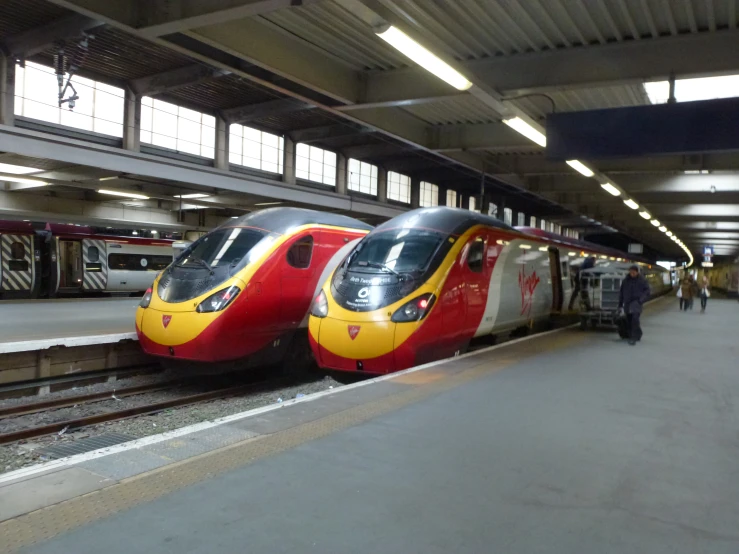 two red and white trains parked on the tracks