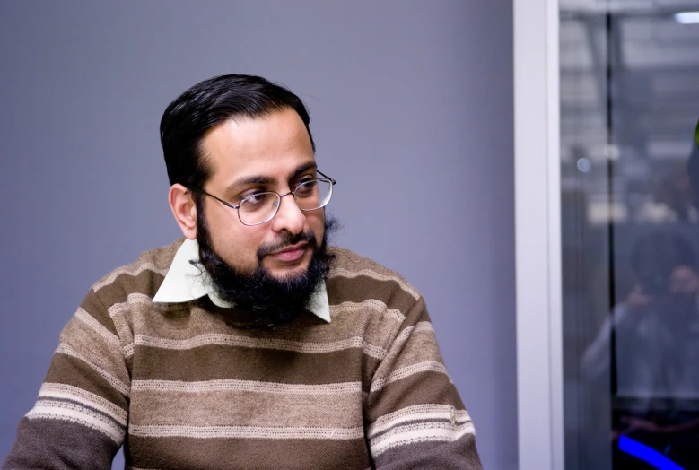 a man with a beard sits at a desk