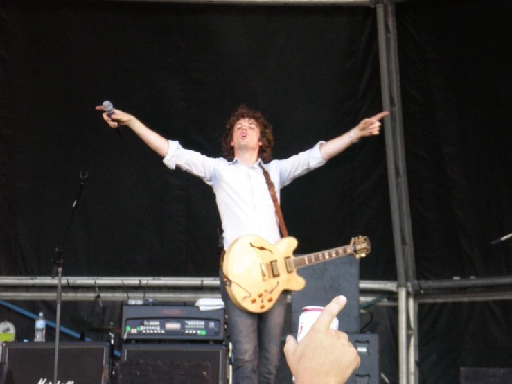a man with his arms in the air while holding up his guitar
